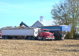 two semi trucks parked in a field next to a barn