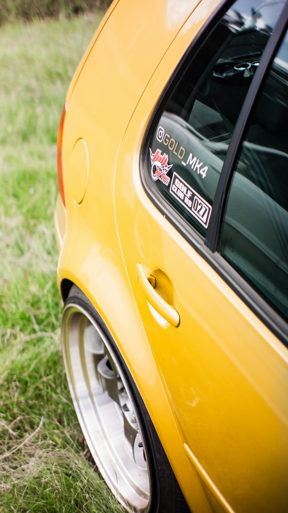 a yellow car parked in a grassy field