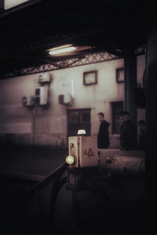 Technician inspecting an industrial electrical control panel with tools in a dimly lit plant.