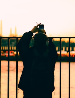 Sunset silhouette of a musician holding headphones and looking at city skyline