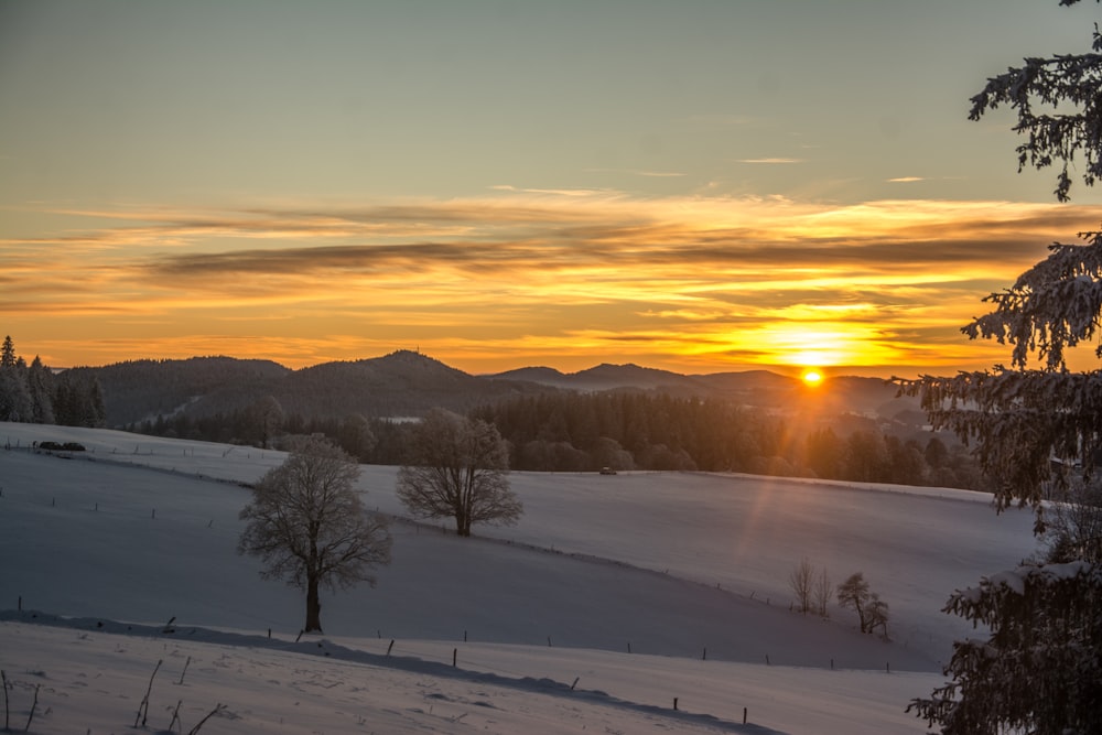 the sun is setting over a snowy landscape
