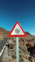 Bright yellow triangular warning sign showing a slippery road symbol.