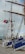 A large sailing ship with tall masts is docked at a port. The masts are adorned with colorful nautical flags, and a Portuguese flag is prominently displayed. People are descending a gangway labeled 'NRP SAGRES PORTUGAL'. A person dressed in a sailor's uniform stands nearby on the dock.
