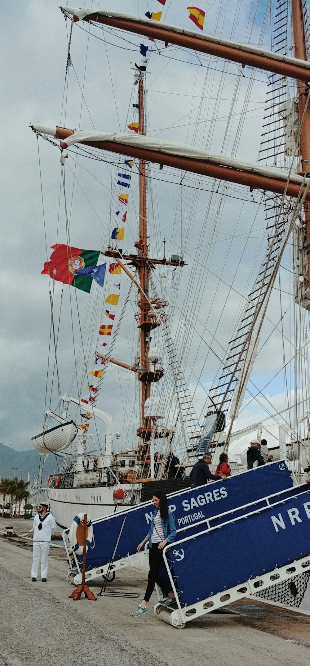 a group of people standing next to a blue and white boat