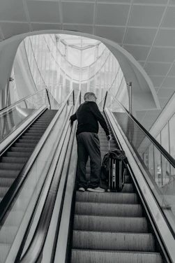 A stylish traveler looking at a luxurious hotel lobby with a suitcase.