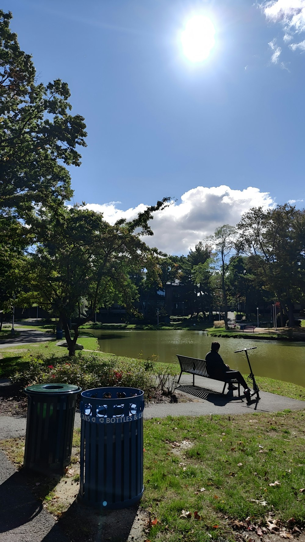 a man sitting on a bench next to a trash can