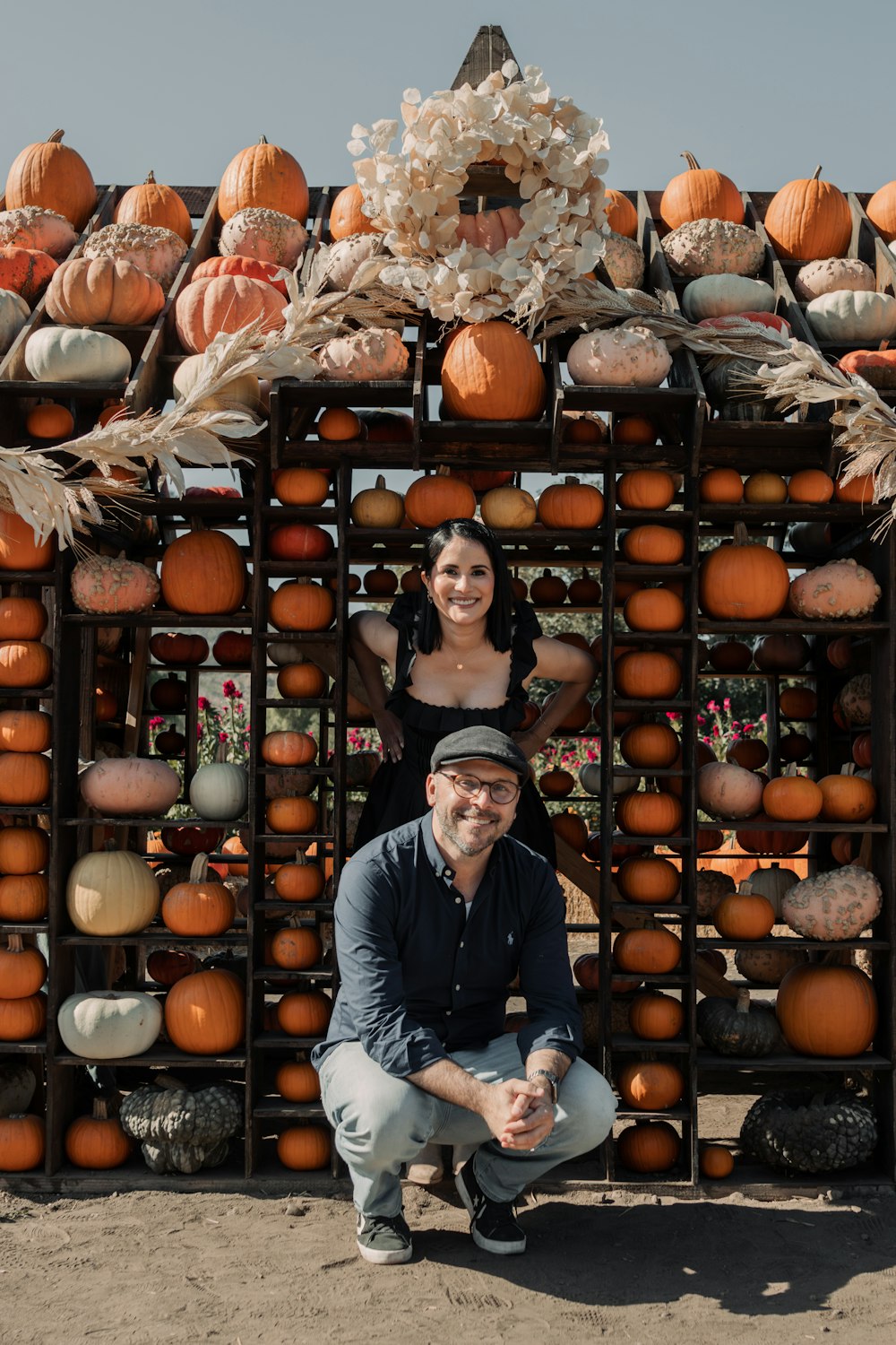 a man and a woman posing in front of a display of pumpkins