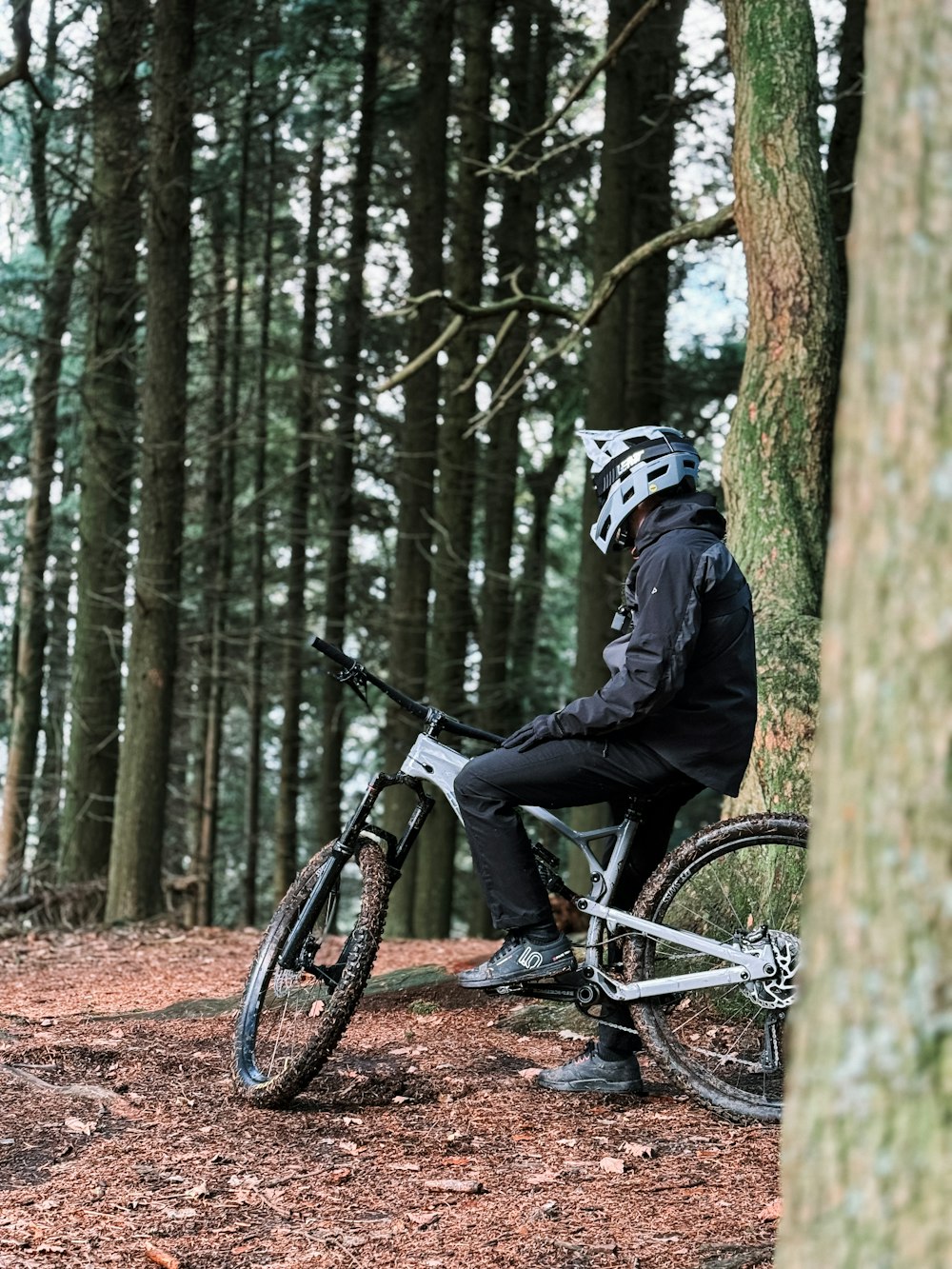 a man sitting on top of a bike next to a tree