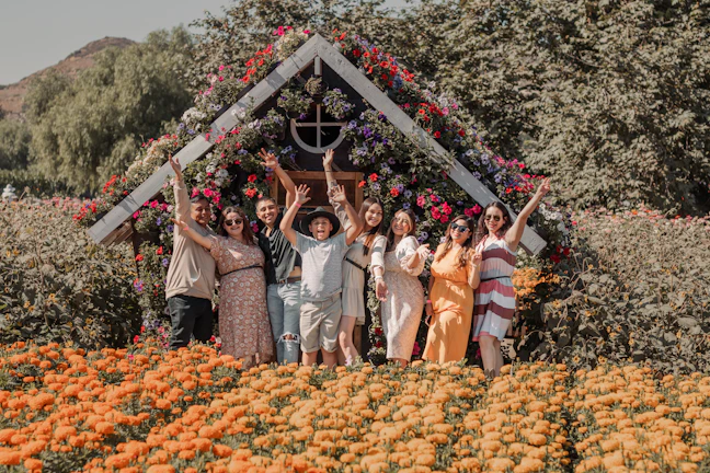 A bright photo of a retirement home group gathered by a colorful flower garden.