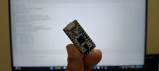 Close-up of a hand holding a soldering iron over a microcontroller circuit board, symbolizing hands-on embedded system work.