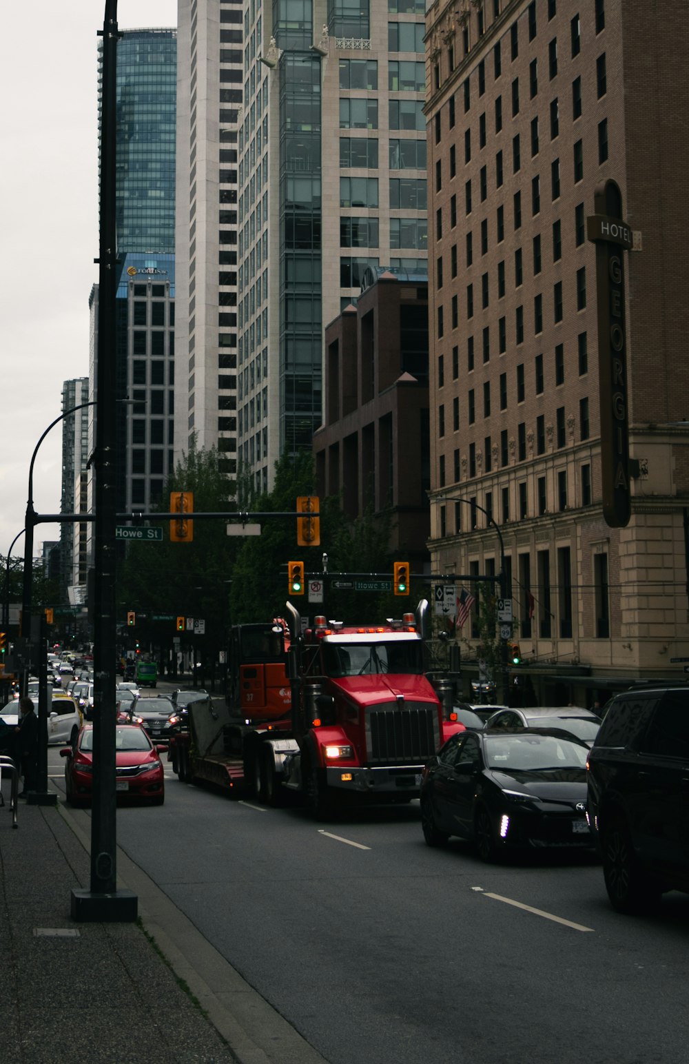 a red semi truck driving down a street next to tall buildings
