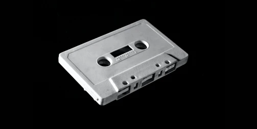 A neon-lit cassette tape glowing against a dark background, capturing the retro 80's vibe.