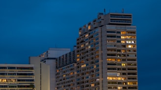 Evening view of a high-rise building with newly installed exterior envelope lit by city lights.