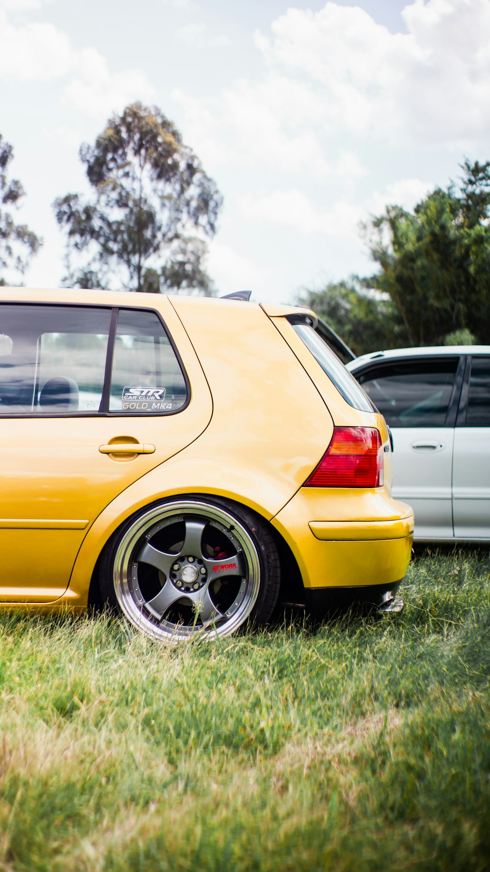 a yellow car parked in a grassy field