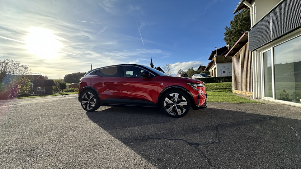 A shiny red family sedan parked outside a suburban home under a bright sky.