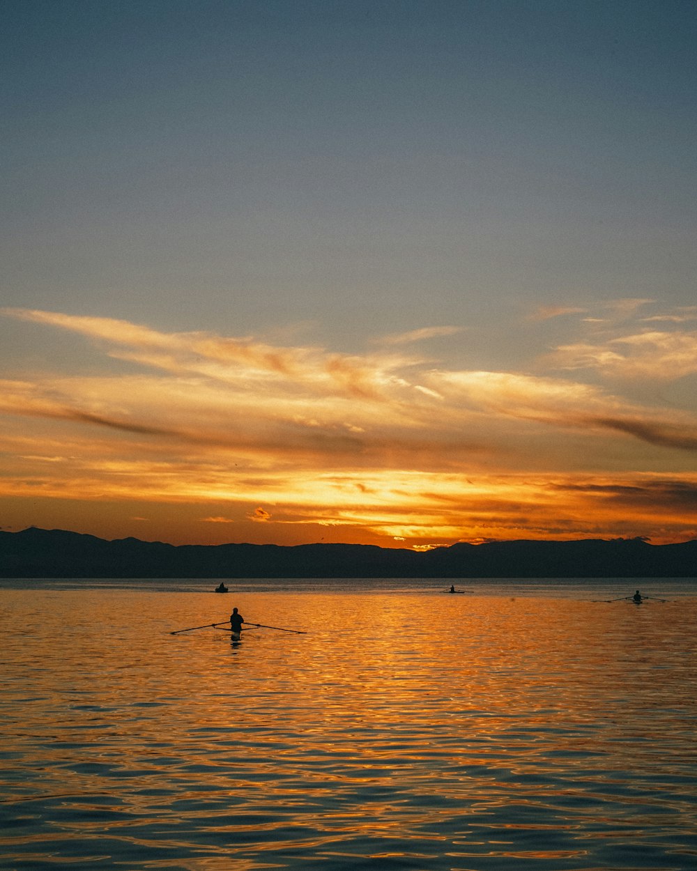 a person rowing a boat in the water at sunset