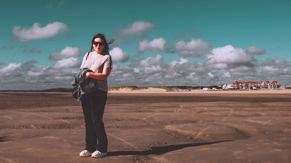 a woman standing on a sandy beach next to the ocean