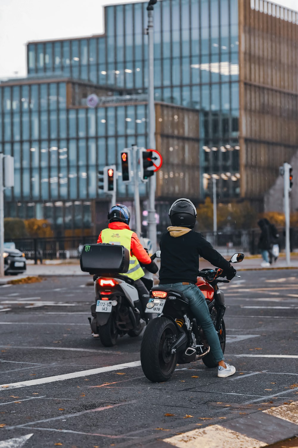 two people riding motorcycles on a city street