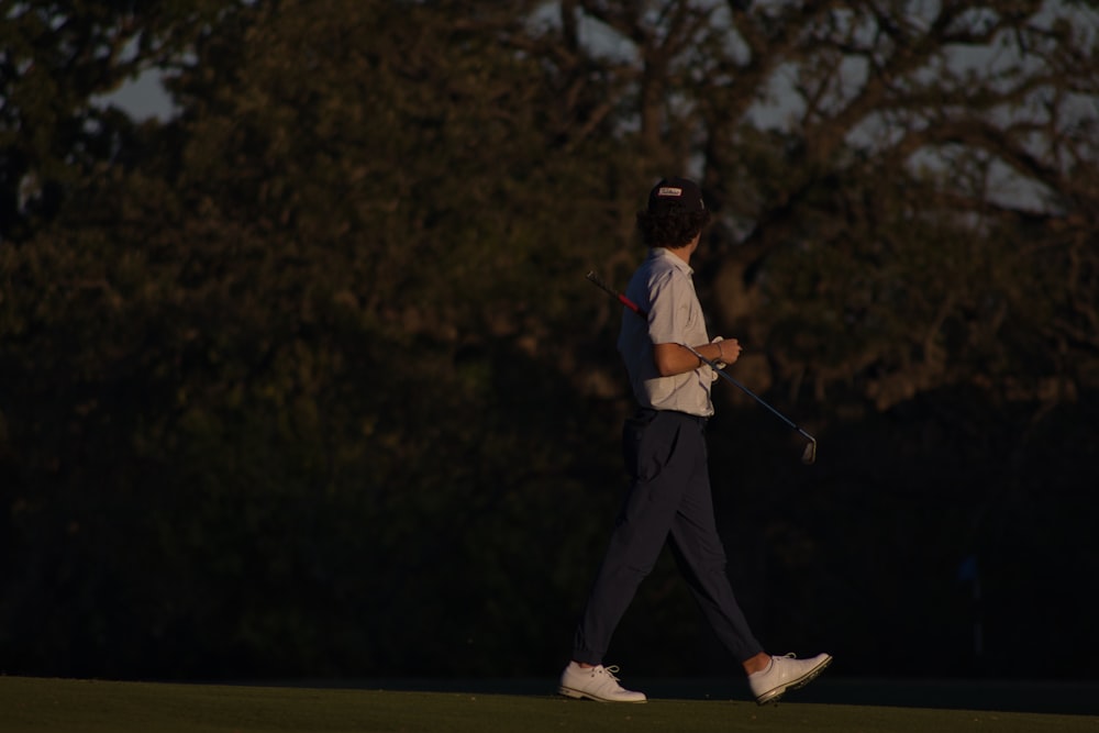 a man walking across a green holding a golf club