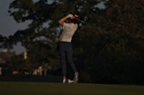 A sleek golfer mid-swing on a misty early morning course, wearing esterl golf apparel.