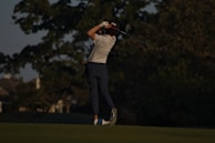 An action shot of a golfer practicing their swing with a launch monitor.