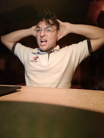 a man sitting at a table with his hands on his head