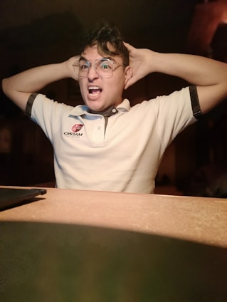 a man sitting at a table with his hands on his head