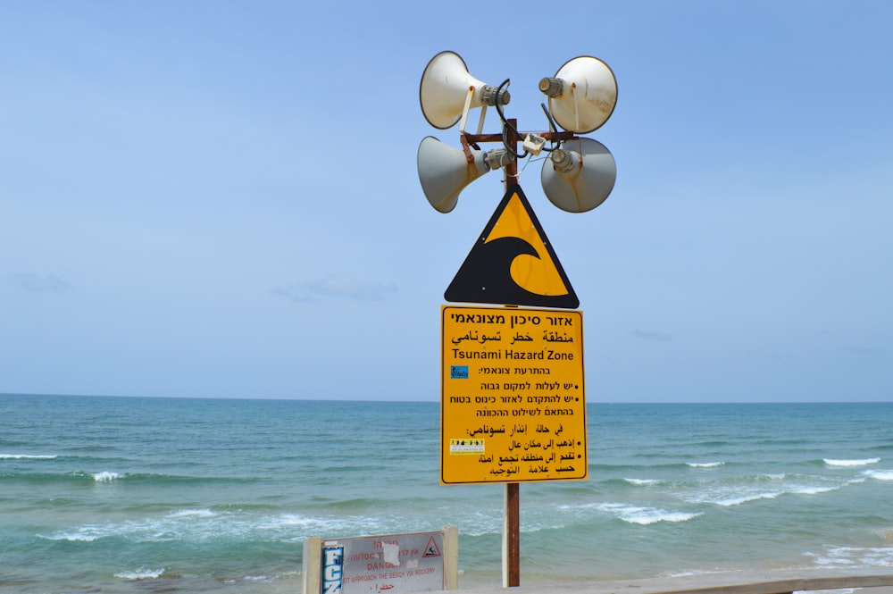 a yellow and black sign sitting on the side of a beach