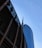 Tall skyscrapers with modern architectural design are seen against a clear blue sky, featuring glass facades. Prominent logos of large corporations appear on the buildings.