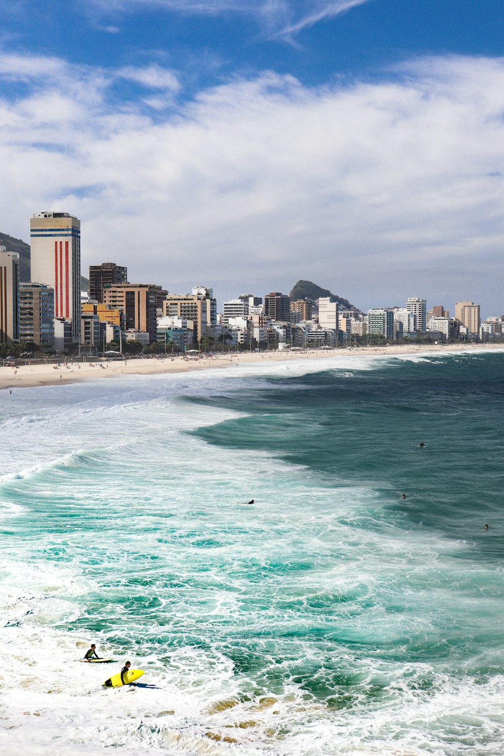 surfers in the ocean with a city in the background
