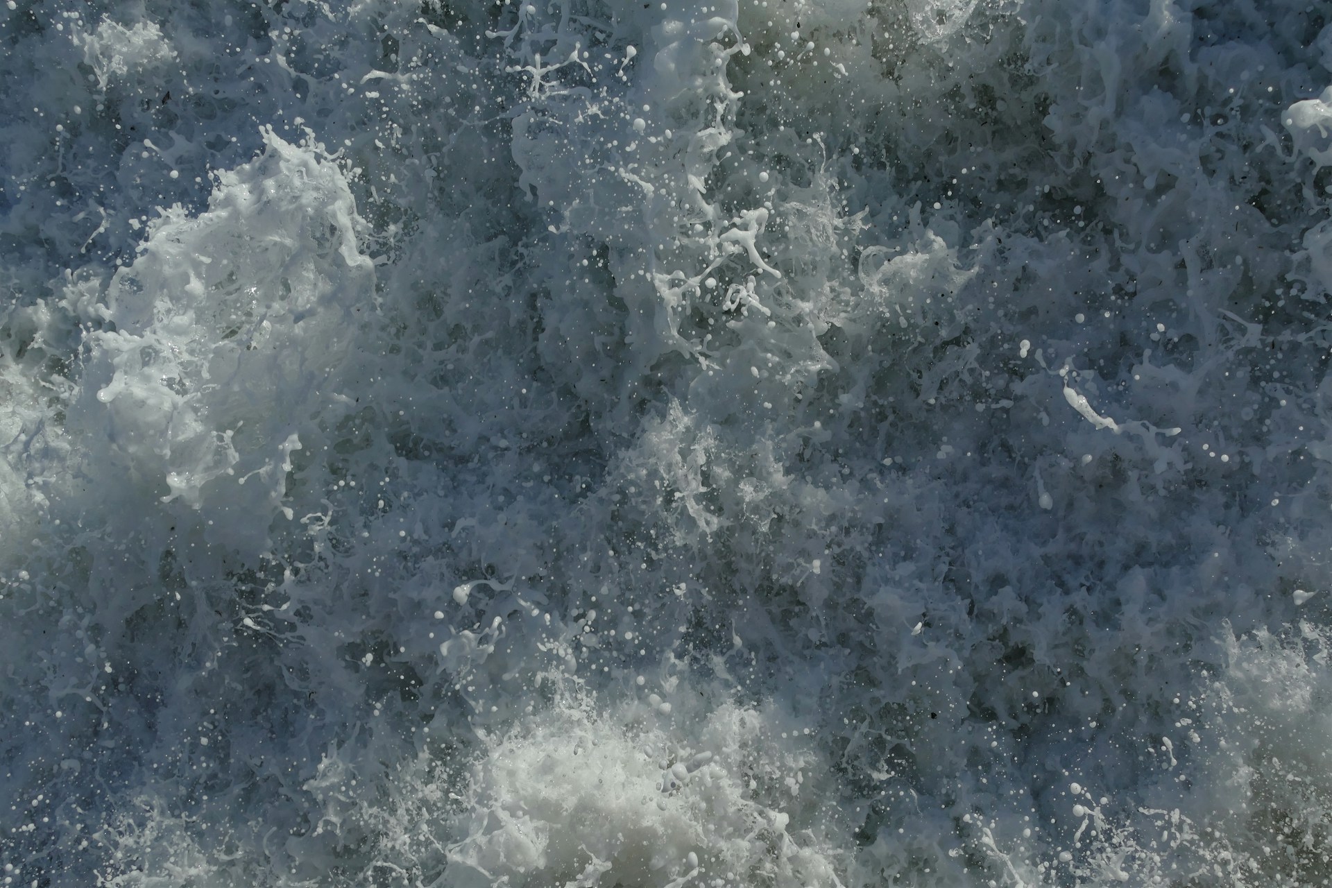 Chaotic and dynamic splashes of water with white foam forming intricate patterns as waves crash.