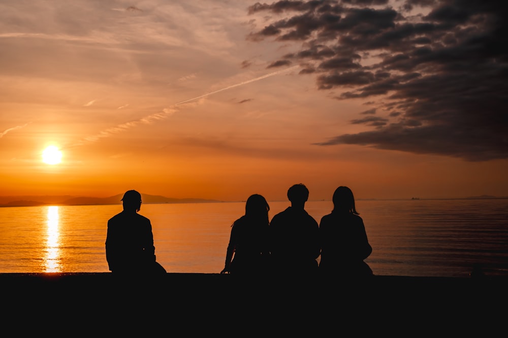 a group of people sitting on a beach watching the sunset