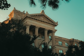 Elegant campus building facade in deep green and gold tones under a clear sky.