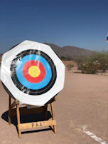 A scenic outdoor shooting range with targets set against a backdrop of trees and blue sky.