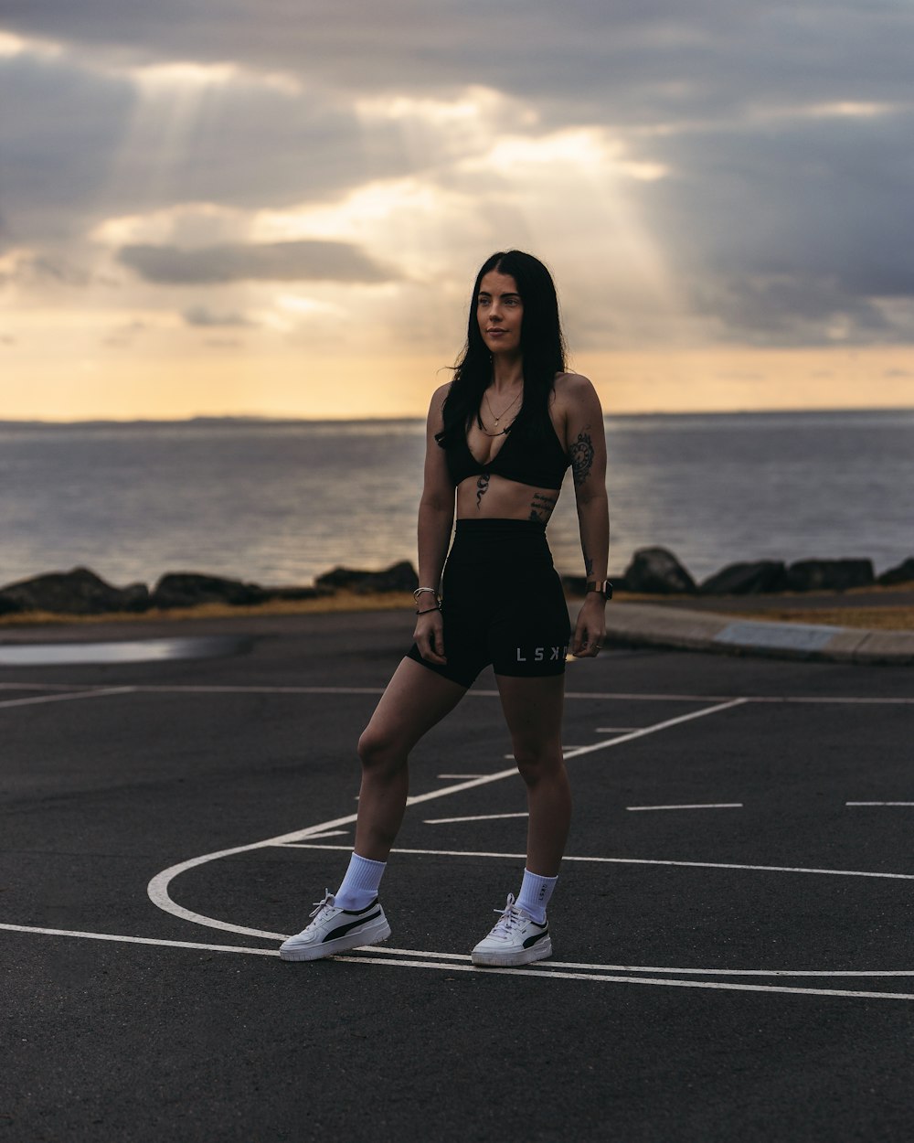 a woman standing in a parking lot next to the ocean