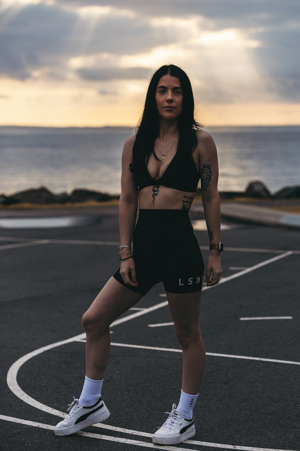 a woman standing in a parking lot next to the ocean