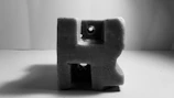 Close-up of a minimalist black sculpture casting sharp shadows on a dark background.