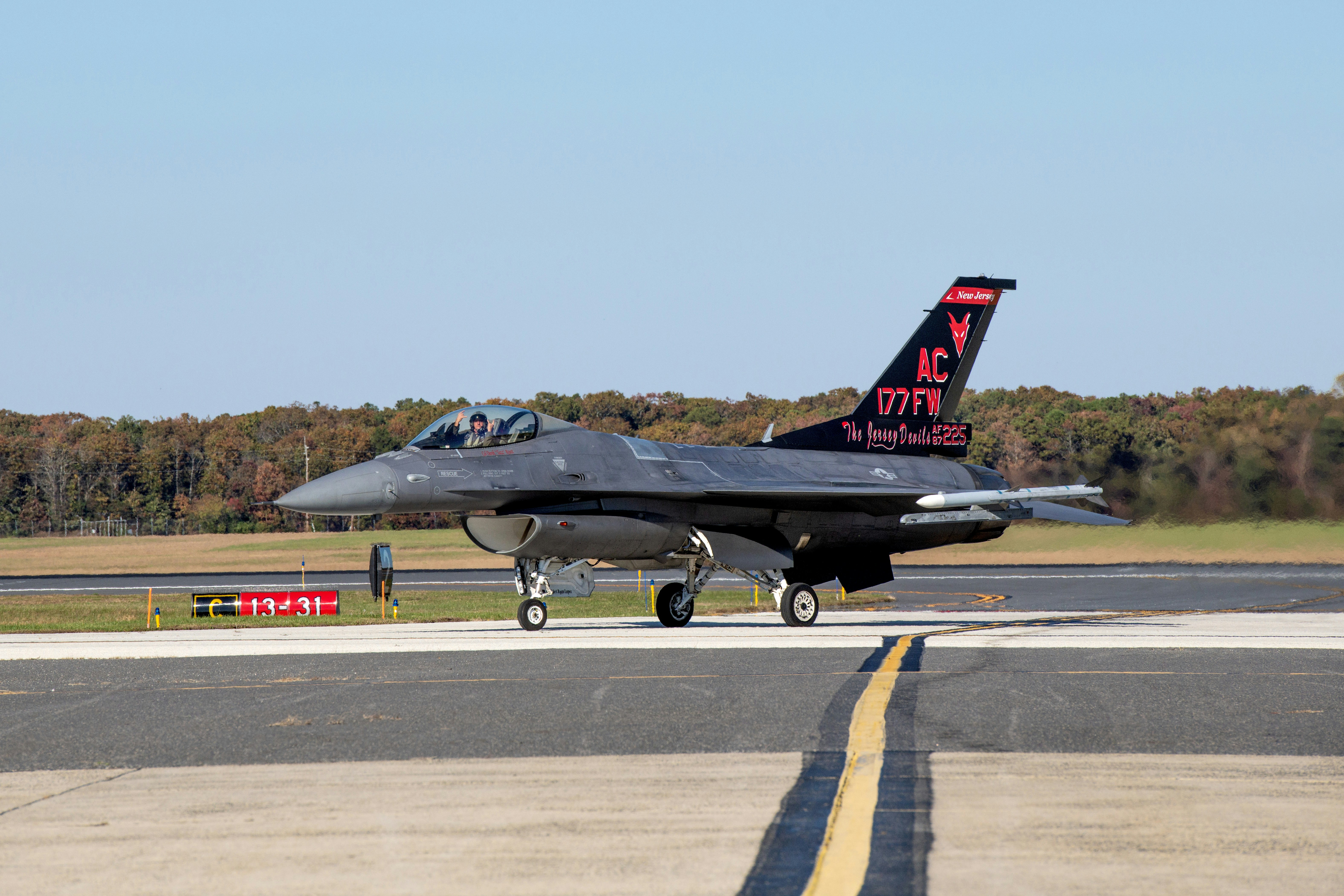 a fighter jet sitting on top of an airport runway, The F-16 for the first time since being decorated with its new tail flash.