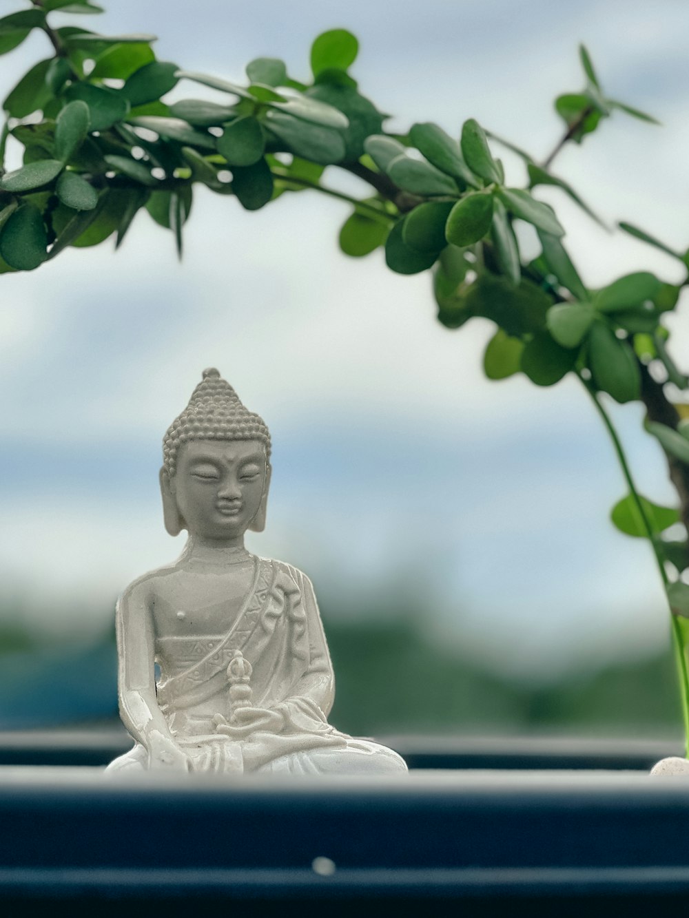 a buddha statue sitting in front of a potted plant
