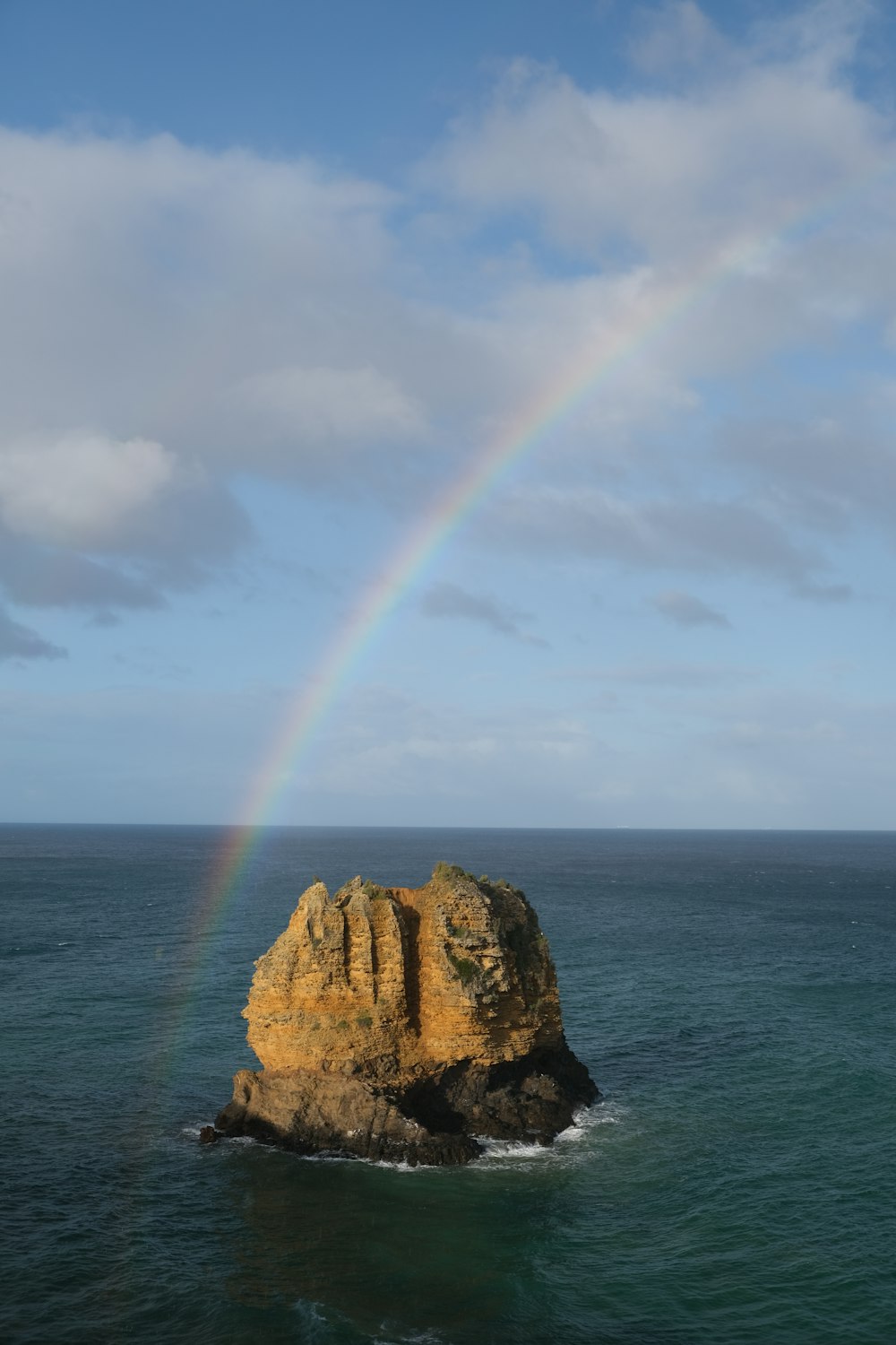 a rainbow shines in the sky over the ocean