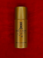 A gold cylindrical spray bottle labeled '1 Million' by Paco Rabanne set against a rich red background.