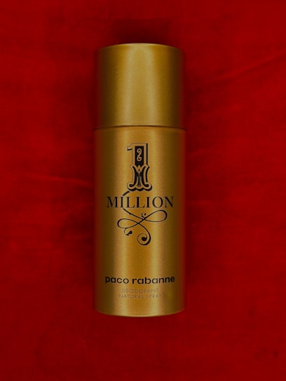 A gold cylindrical spray bottle labeled '1 Million' by Paco Rabanne set against a rich red background.