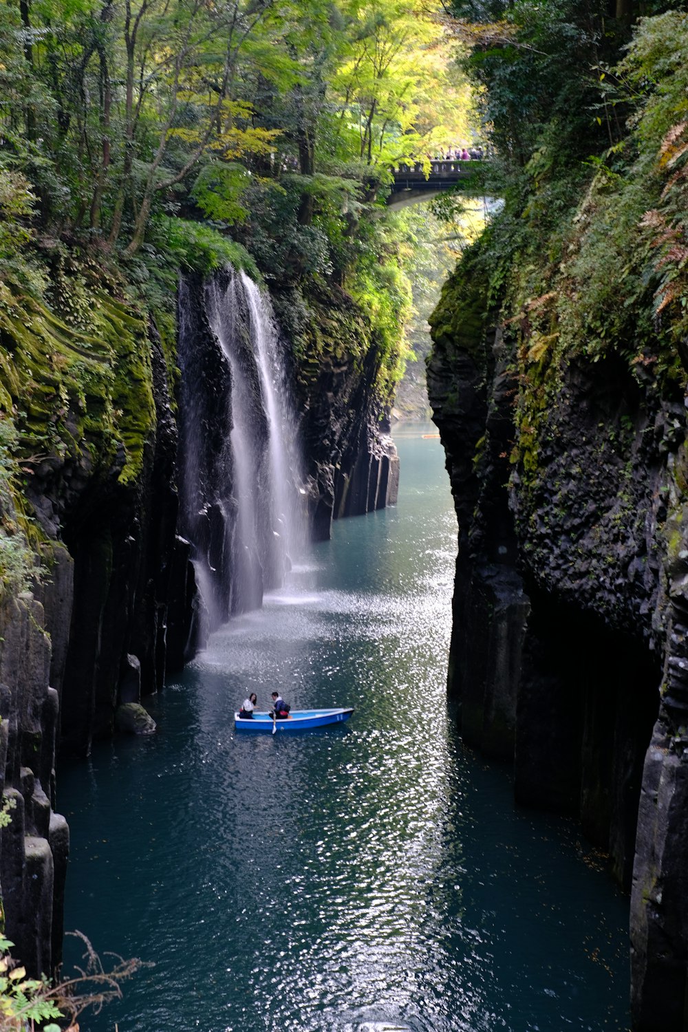 a boat in a body of water near a waterfall