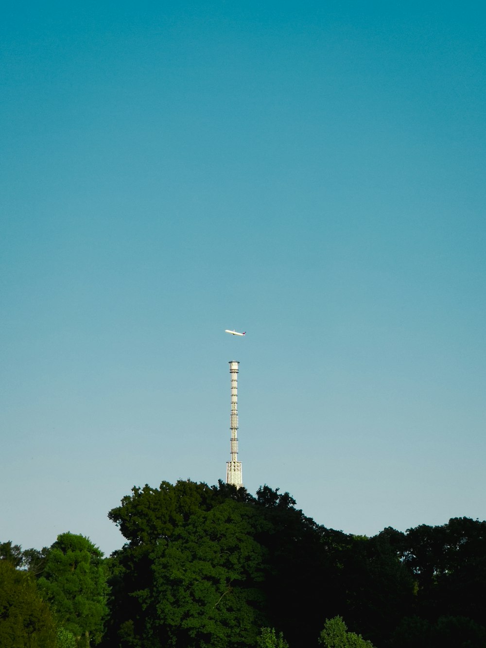 an airplane is flying over the top of a tower