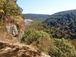 Tourists enjoying panoramic views from a rocky viewpoint with autumn foliage