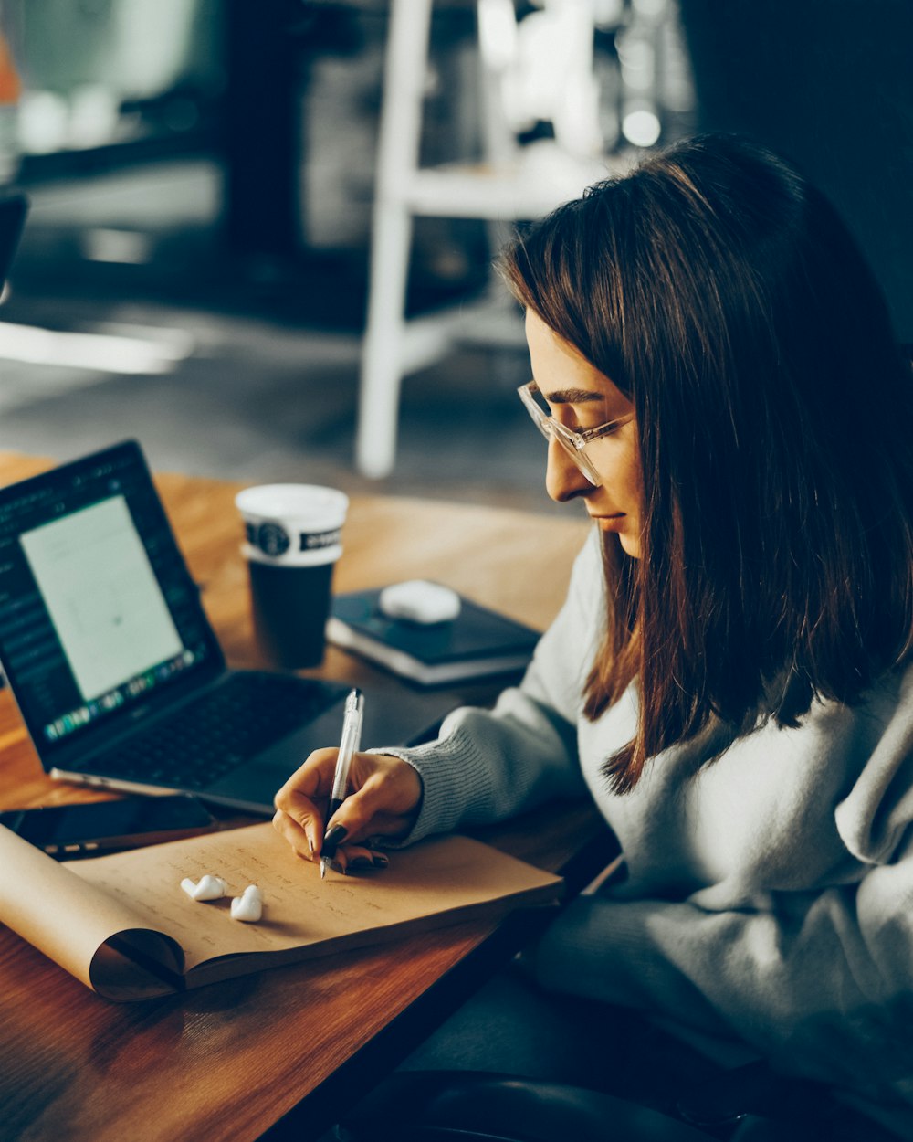 a woman sitting at a desk writing on a piece of paper