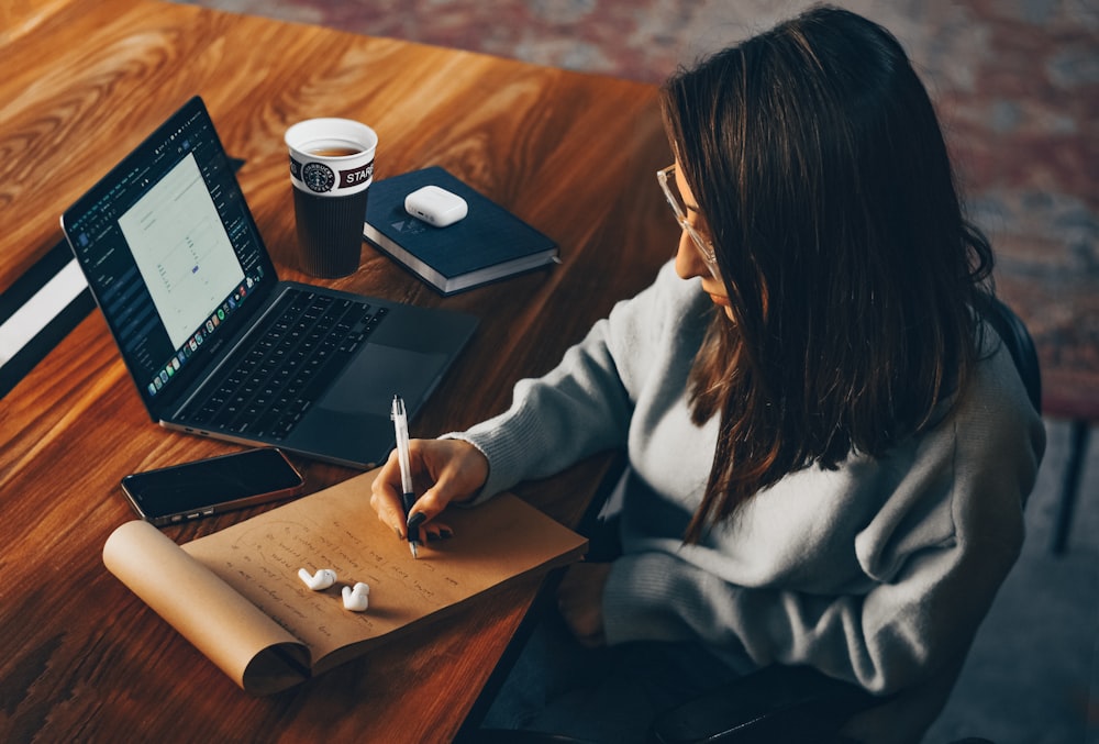 a woman sitting at a table writing on a piece of paper