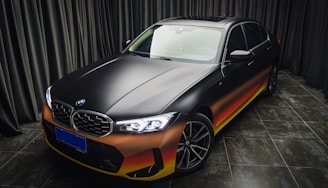 a black and orange car parked in front of a curtain
