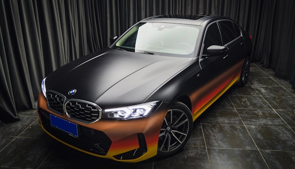 a black and orange car parked in front of a curtain