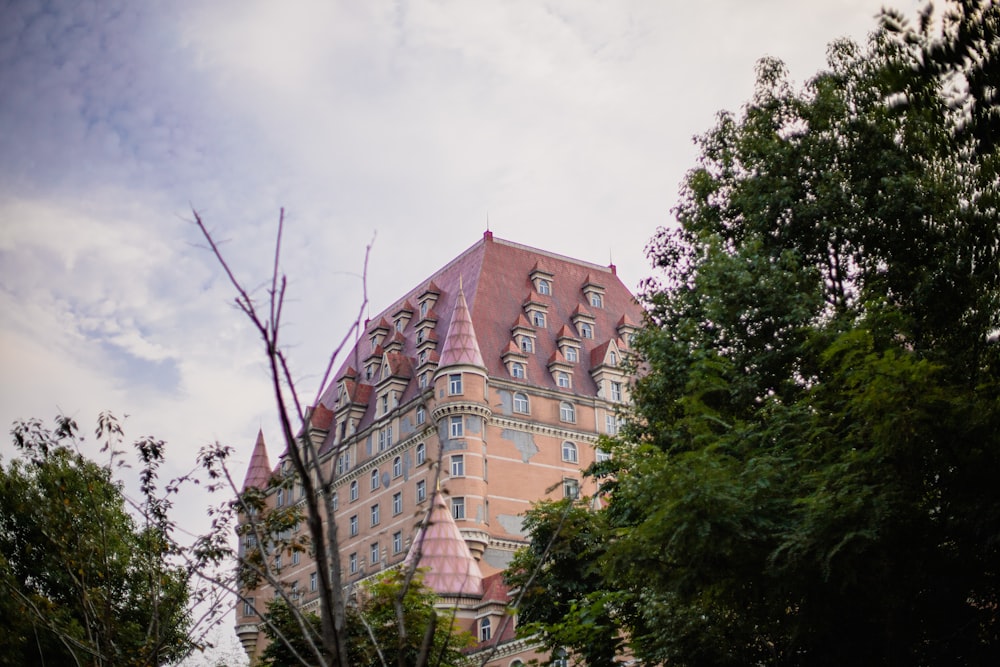 a tall building with a pink roof surrounded by trees